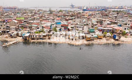 Slums in Manila near the port. Houses of poor inhabitants. A lot of garbage in the water, Philippines, top view. Stock Photo