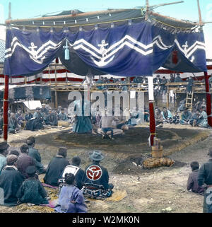 [ 1900s Japan - Sumo Wrestlers at Outside Arena, Tokyo ] —   Sumo wrestlers in an outside arena at Eko-in Temple (回向院) in Ryogoku, Tokyo ready to start a bout. The temple was known as a sumo wrestling venue during the Edo (1603-1868) and Meiji (1868-1912) periods. The first bout was held here in September 1768. From October 1833 (Tenpo 4) to 1909 (Meiji 42), the period of 'Eko-in Sumo' (回向院相撲), all sumo tournaments were held at the temple.  20th century vintage glass slide. Stock Photo