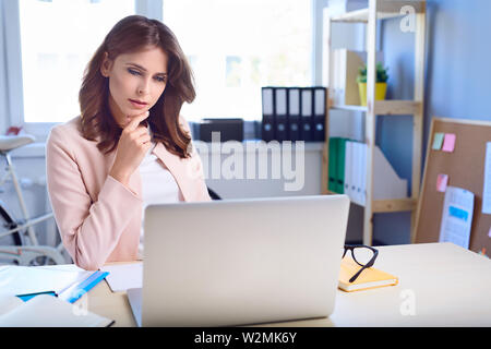 Thoughtful woman working on her laptop Stock Photo