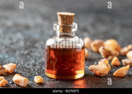 A bottle of styrax benzoin essential oil and resin on a dark background.