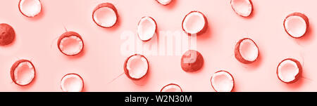 Pattern with ripe coconuts on trendy coral color background. Top View. Copy Space. Pop art design, creative summer concept. Half of coconut in minimal Stock Photo