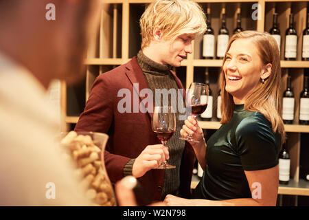 Hilarious young couple having a wine tasting with red wine in bar or wine shop Stock Photo