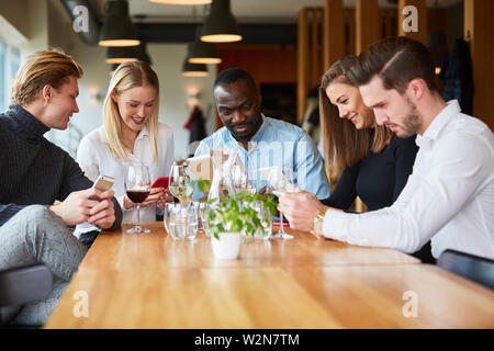 Young people in the restaurant are constantly looking at their smartphone or mobile phone Stock Photo
