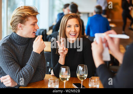 Young couple in the bistro or restaurant ordered food from waiter or waitress Stock Photo