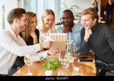 Young start-up team looks at tablet in the restaurant at a meeting Stock Photo