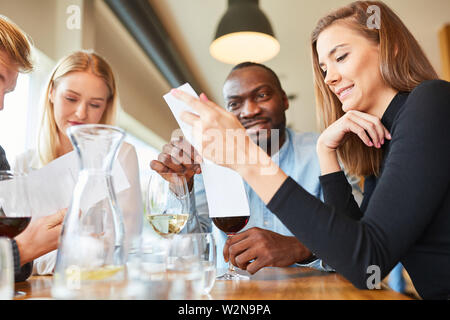 Group of guests in the bistro or restaurant read the menu and think twice Stock Photo