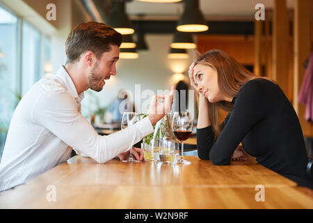 Couple sits arguing and discussing wine in the restaurant Stock Photo