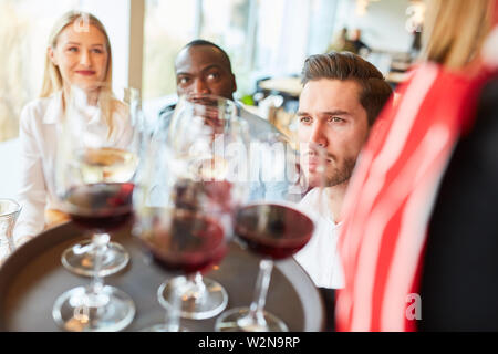 Waitress serves guests on a tray glasses with red wine in the restaurant Stock Photo