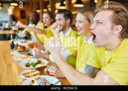 Group of football fans cheers team at the public viewing in the restaurant Stock Photo