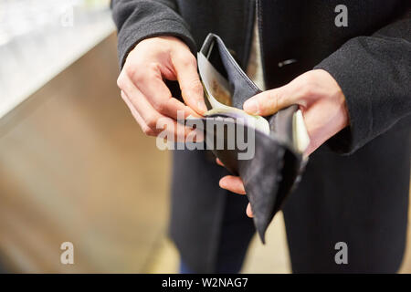 Man with wallet paying with cash in restaurant or retail Stock Photo