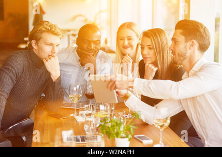 Group at meeting in restaurant looks together on tablet computer Stock Photo