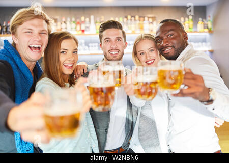 Laughing group of friends drinking beer in the pub in a cheerful mood Stock Photo