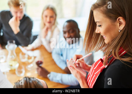 Young waitress in the restaurant notes the order of guests on a notepad Stock Photo