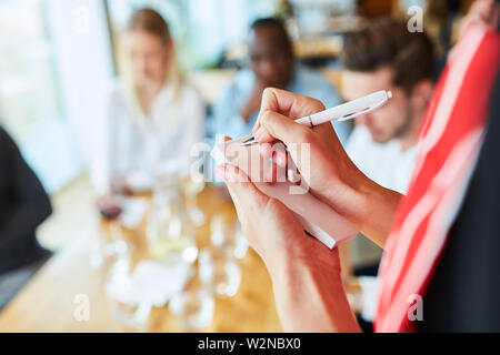 Service staff in training notes the order of the guests in the restaurant Stock Photo