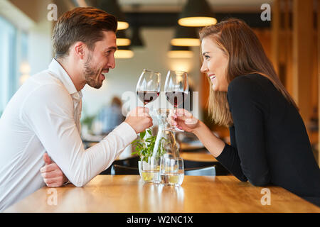 Amorous young couple having a rendezvous at the restaurant drinking a glass of red wine Stock Photo