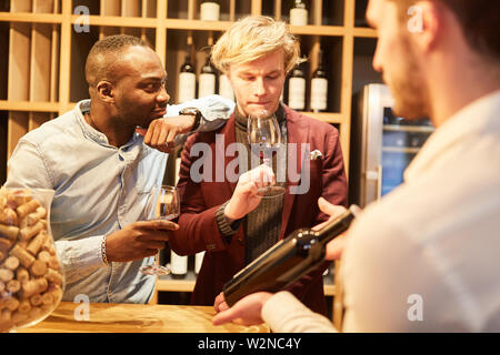 Young people having sommelier at a wine tasting or tasting in a bar Stock Photo