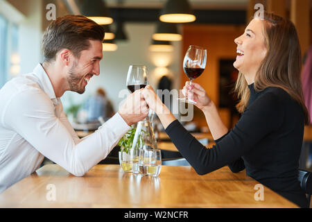 Young man holds hand to his laughing girlfriend while dating in restaurant Stock Photo