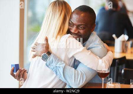 Happy multicultural couple hugging each other while dating in the restaurant Stock Photo