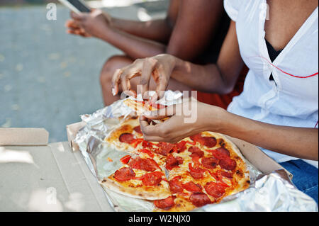 Hands of african american woman with pizza. Stock Photo