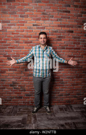 Male portrait Italian, good positive emotions against the background  fire wall in style loft. In klechatoy shirt, jeans and sneakers, urban clothing. Stock Photo