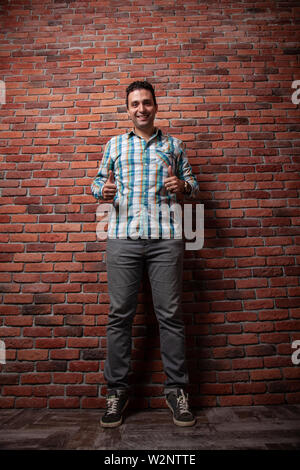 Male portrait Italian, good positive emotions against the background  fire wall in style loft. In klechatoy shirt, jeans and sneakers, urban clothing. Stock Photo