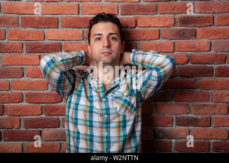 Male portrait Italian, good positive emotions against the background  fire wall in style loft. In klechatoy shirt, jeans and sneakers, urban clothing. Stock Photo