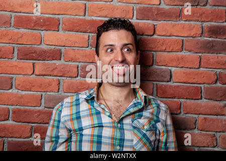 Male portrait Italian, good positive emotions against the background  fire wall in style loft. In klechatoy shirt, jeans and sneakers, urban clothing. Stock Photo