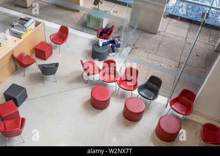 Looking down on a person sitting on a colourful chair in the lower ground floor of the New South Wales State Library in Macquarie Street, Sydney Stock Photo