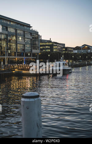 Pyrmont, New South Wales - JUNE 28th, 2019: Looking out at a boat on the water from Pyrmont Bay Park. Shot just after sunset at dusk. Stock Photo