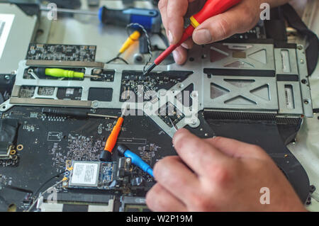 a man repairs a computer, solders a board, repairs electronics and modern technologies Stock Photo