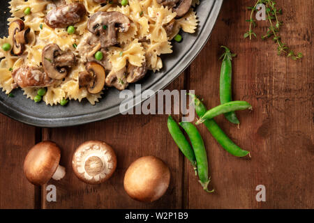 Mushroom and cheese pasta. Farfalle with cremini and green peas close-up