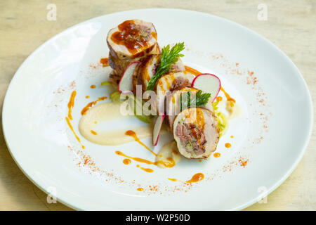 close up of a sliced stuffed pork loin roasted roll with sausage, vegetable, puree, barbecue sauce , professional italian chef food in a fine dining r Stock Photo