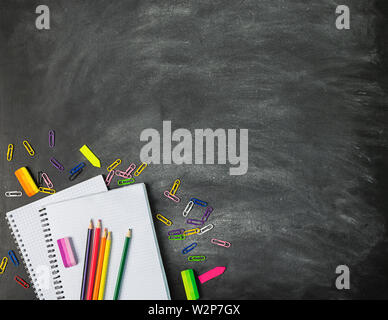 Educational supplies notebooks pens pencils against the background of a chalk board. Concept back to school. Flat layout Stock Photo