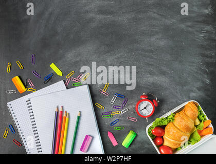 Sandwich teaching supplies notebook pen on a chalk board. Concept back to school. Top view flat layout. Stock Photo