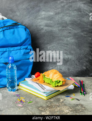 Sandwich training supplies notebooks blue backpack against the background of the chalk board. Concept back to school. Stock Photo