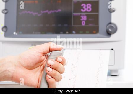 Close-up shot of pregnant woman's hand holding controller of the Cardiotocograph machine aka Electronic Fetal Monitor (EFM) recording the fetal heartb Stock Photo