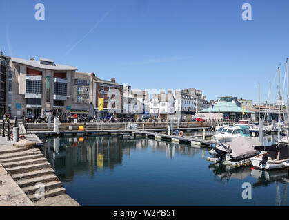 A visitor centre, shops, cafes and restaurants line the waterfront at Plymouth Sutton Harbour. Stock Photo