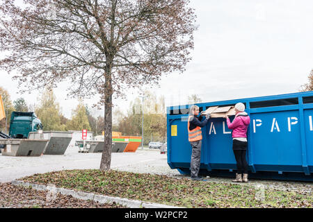 Woman and man putting waste paper in container at recycling center Stock Photo