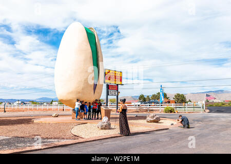 Alamogordo, USA - June 9, 2019: New Mexico pistachio tree farm with the world's largest statue of nut and people posing by sign Stock Photo