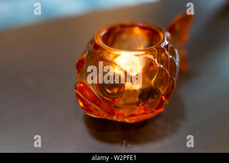 Closeup of glass object with illuminated lit tea candle lamp on table traditional Japanese goldfish decoration Stock Photo