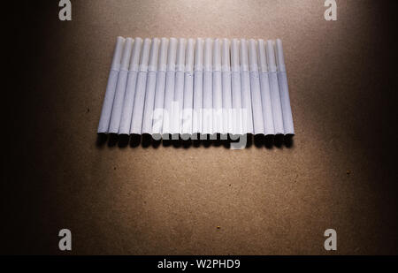 Abstract composition of bunch of cigarettes on brown surface. Stock Photo