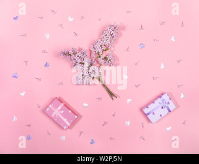 Twigs and flowers of lilac and gift boxes on pink background. Stock Photo