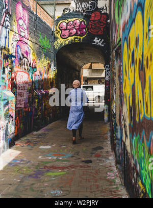 Woman walking down Graffiti street, Legal street art - UNESCO world heritage Stock Photo