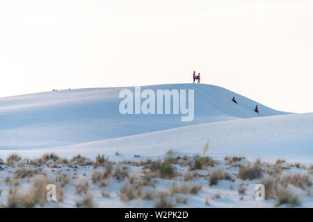 La Luz - June 9, 2019: White sands dunes national monument gypsum sand and plants in New Mexico with horizon at sunset and people family in distance Stock Photo