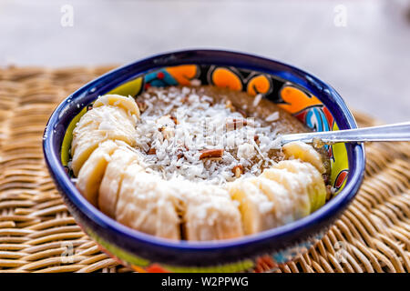 Closeup of colorful bowl with amaranth porridge and sliced bananas with shredded coconut and pecan pieces Stock Photo