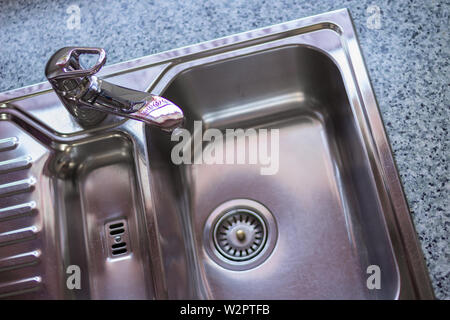 Kitchen sink Concept. Clean Chrome sink in a modern kitchen with copy space. Marble countertop Stock Photo