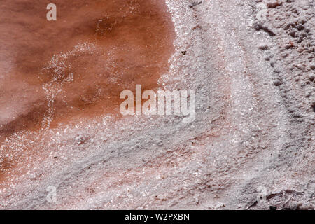 Closeup of the border of a salt pan in the colors white and orange | The water has already partially evaporated Stock Photo