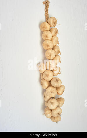 A bunch of garlic on the white background of the wall.Kitchen and cooking. Stock Photo