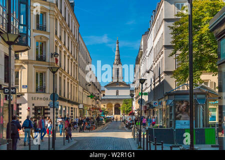 Street view of Rue du Commerce with its shops and the neo-Gothic catholic church Église Saint-Jean-Baptiste de Grenelle at the end of the road on a... Stock Photo
