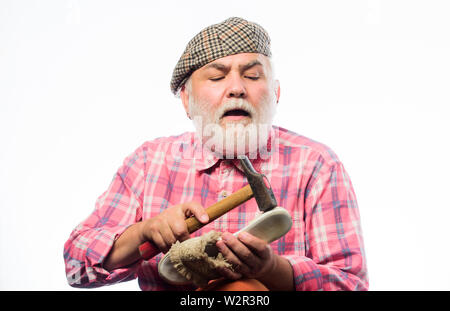 mature shoemaker in workshop make shoes. Cobbler workmanship. shoemaker working with leather textile and hammer at workshop. retro man repair shoes with hammer. shoemaker at work. at shoe store. Stock Photo